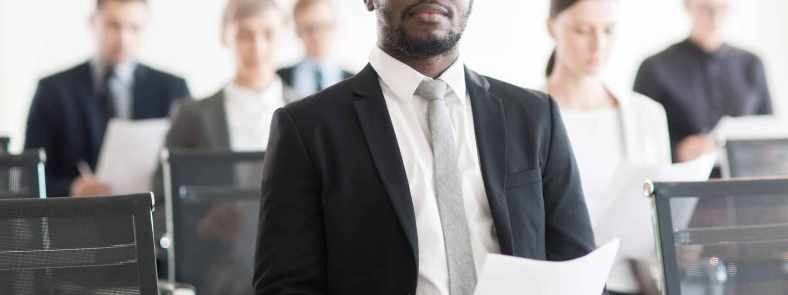 Young African-american businessman in formalwear sitting in conference hall and waiting for his turn