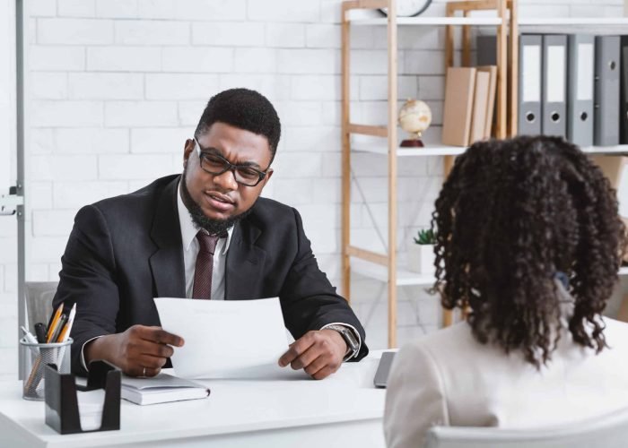 Job search concept. Serious HR manager looking through applicant's resume during employment interview at office