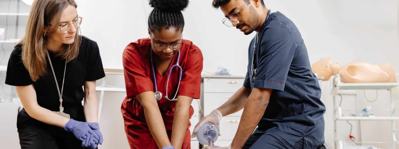 Diverse group of medical students practicing cpr on a medical manikin during first aid training in a hospital or clinic setting